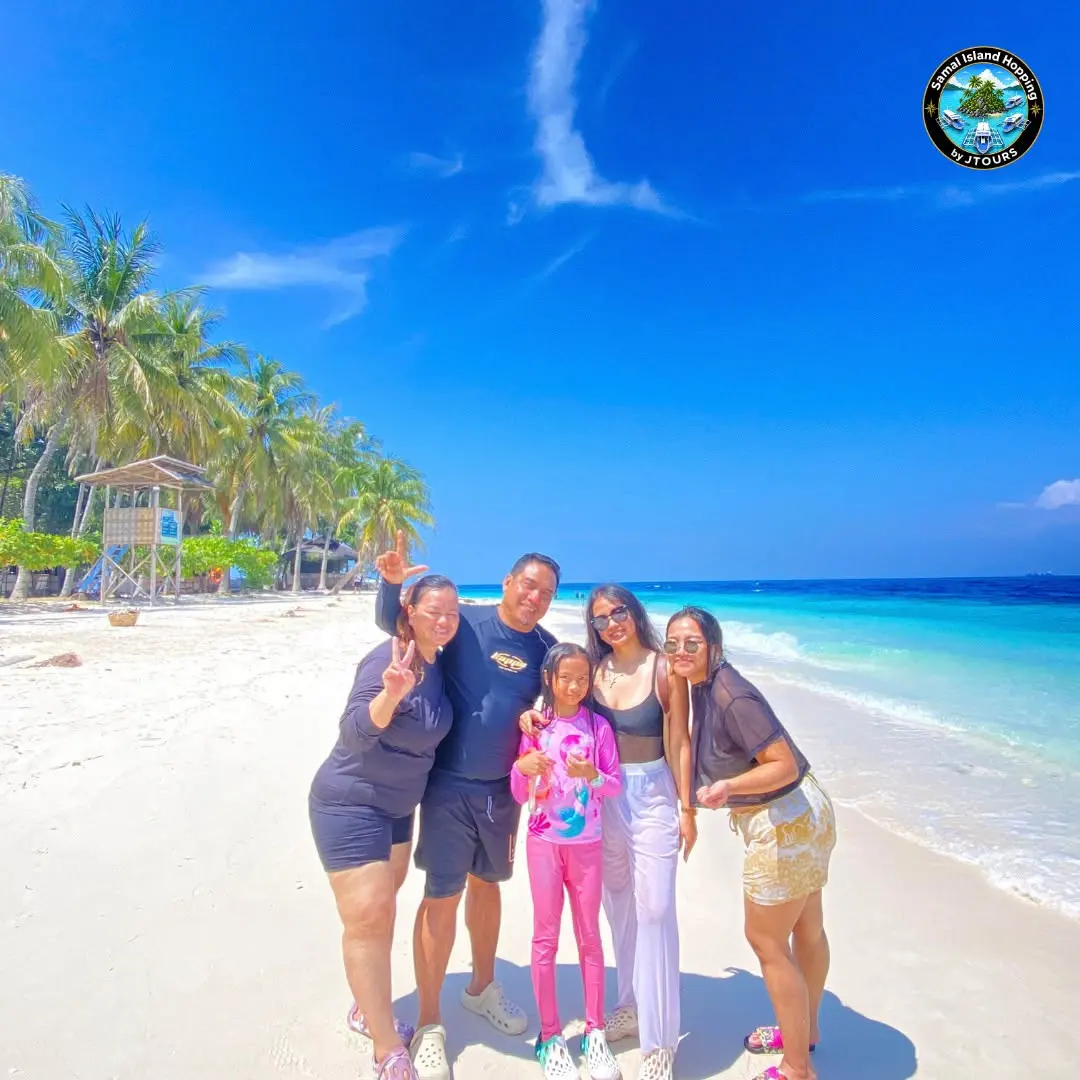 Family posing on a white-sand beach with palm trees