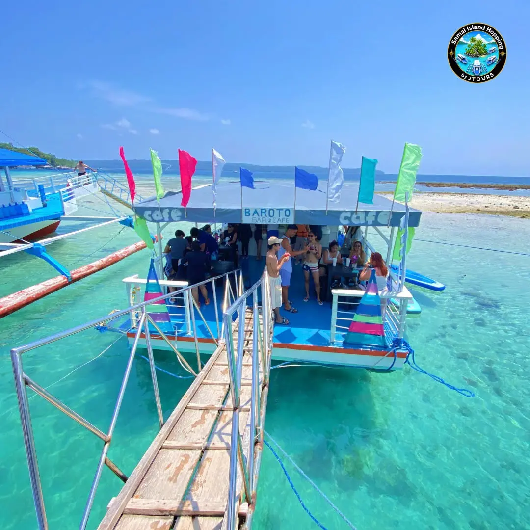 Island-hopping boat with a wooden plank walkway over turquoise shallows