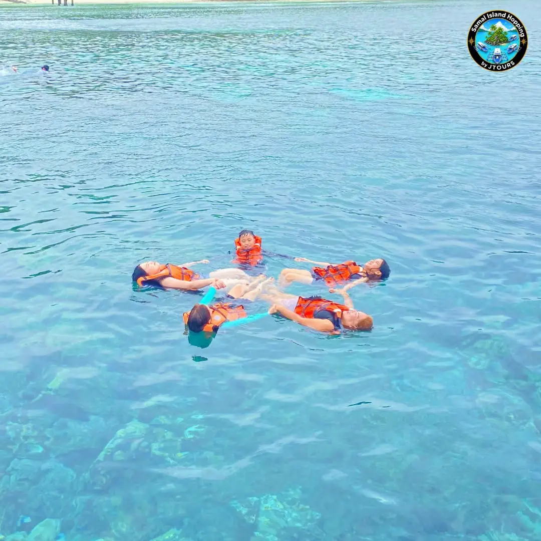Snorkelers in orange life vests floating together in clear water