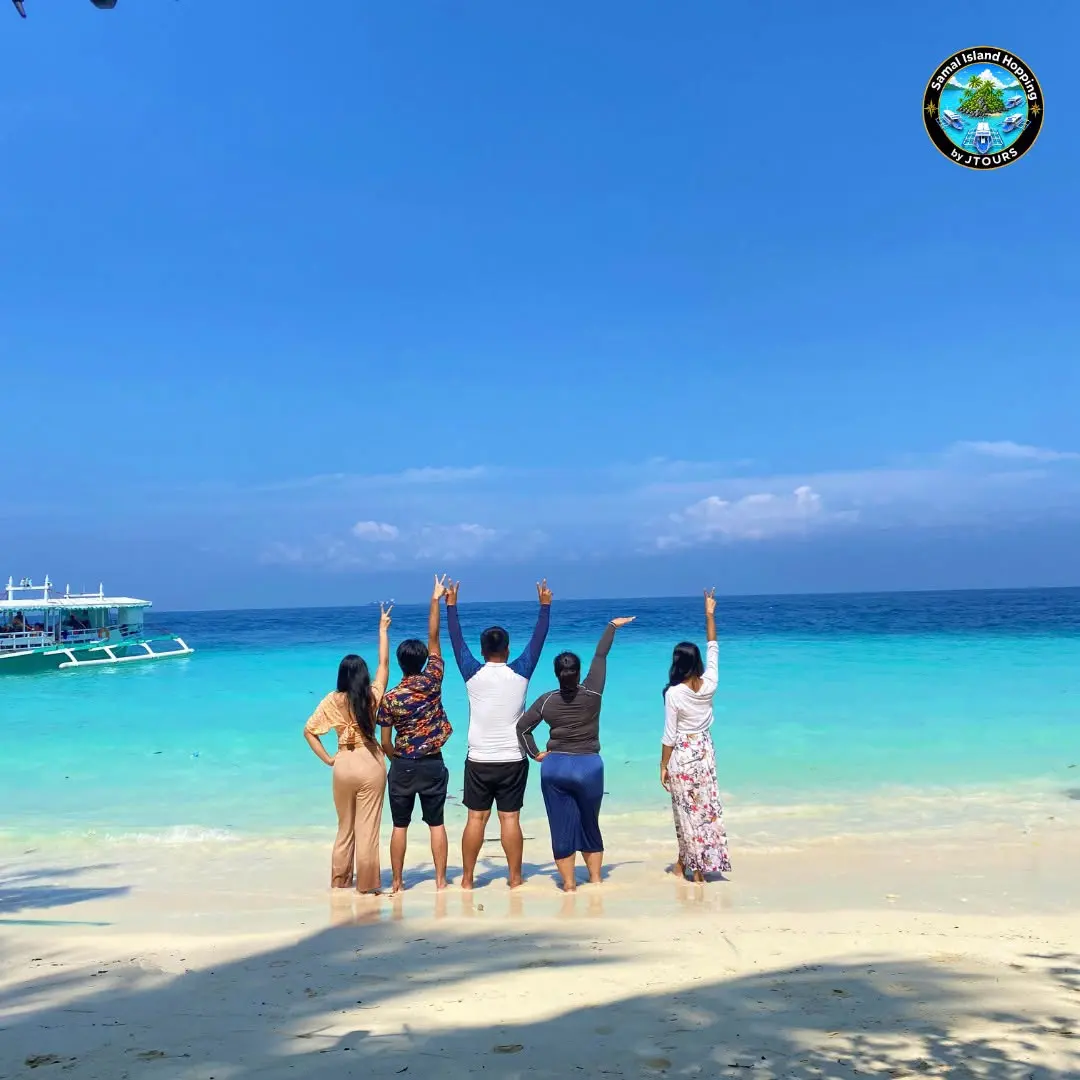 Guests with arms raised at the shoreline looking out to sea