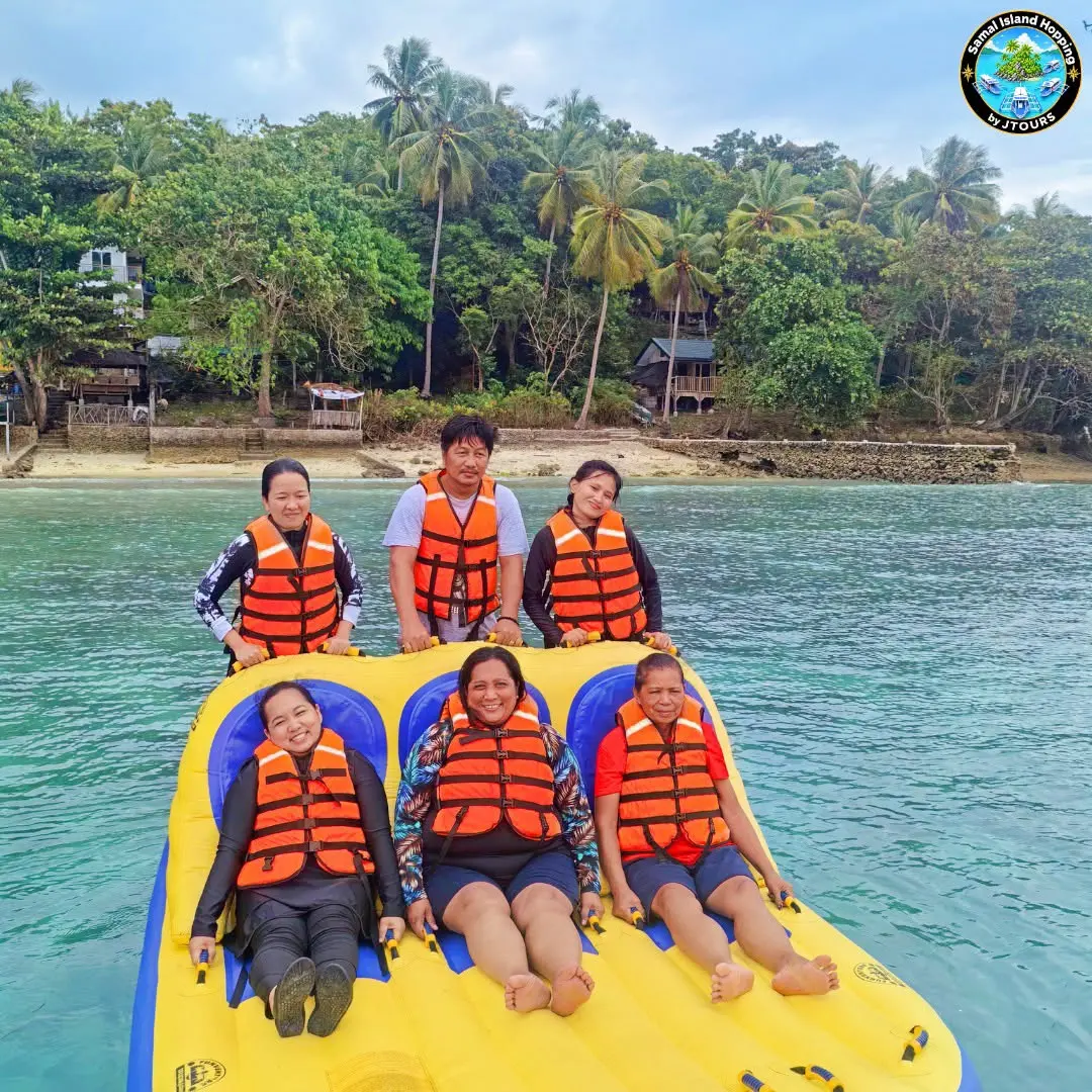 Guests in orange life vests on a yellow inflatable raft off the island shore