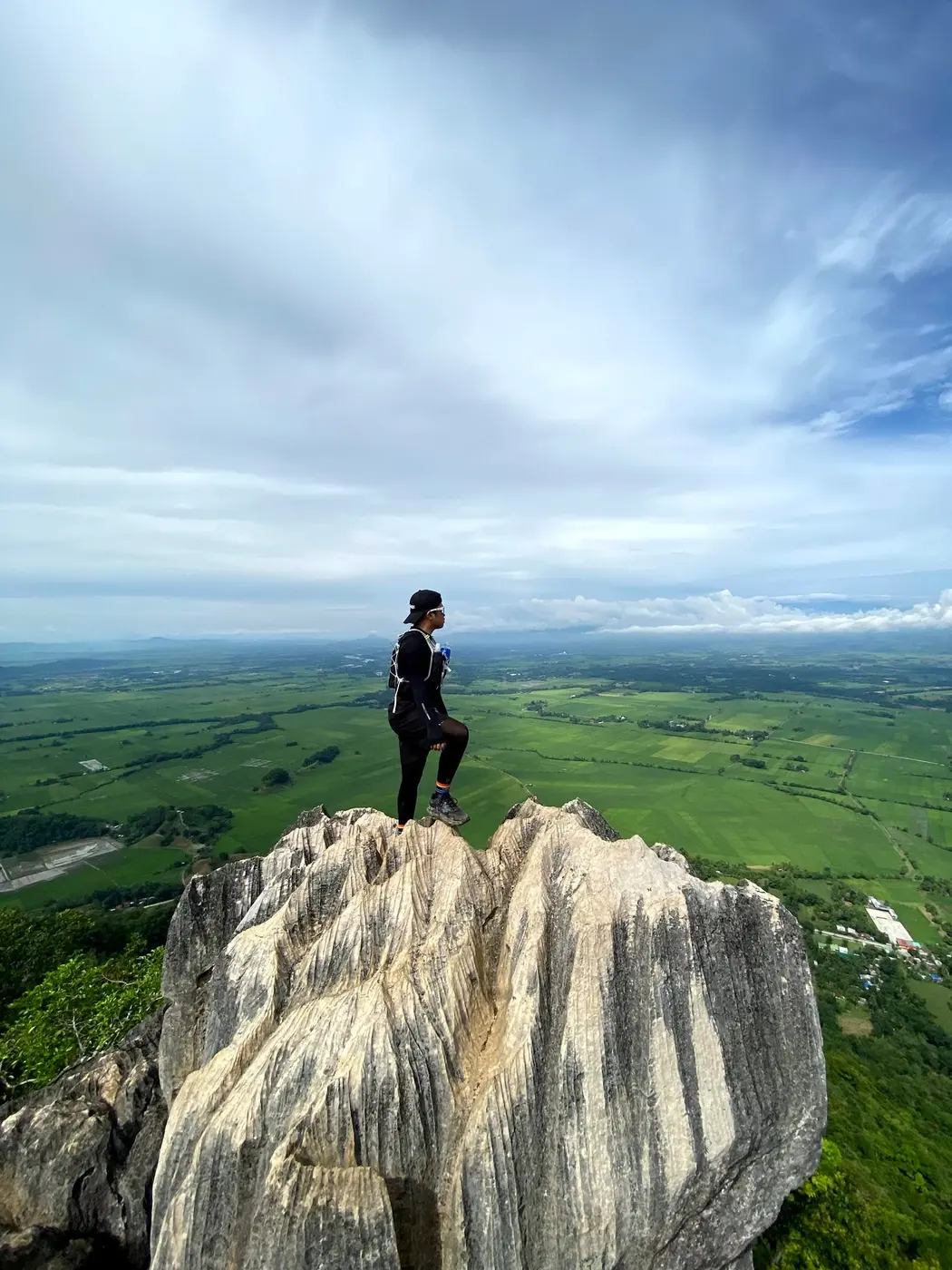 Hiker standing on a limestone peak above green plains
