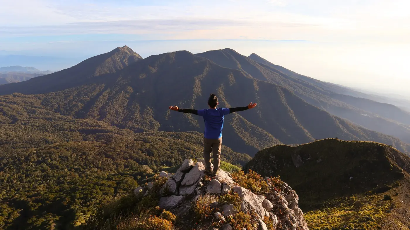 Hiker with arms outstretched on a mountain summit